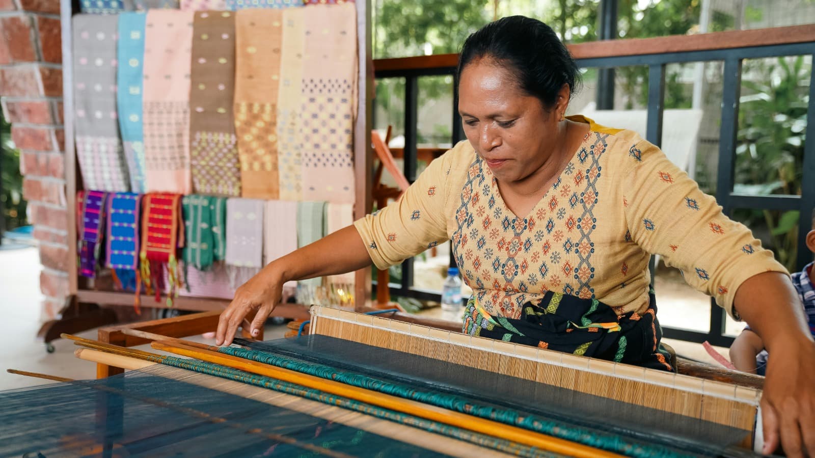Artesana tejiendo en telar tradicional, representando a las comunidades locales que apoya Raíz del Lugar